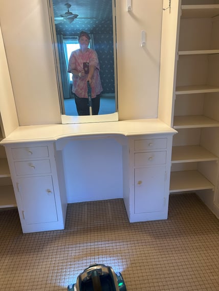 Heidi vaccuuming in childhood home by built-in vanity table-shelves_2