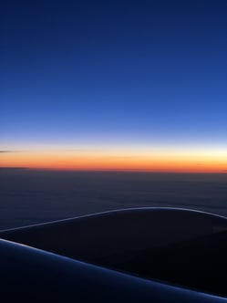 A vertical view from an airplane window, focusing closely on the transition from dark wing to twilight horizon, illustrating the specific childhood memory and the feeling of the "window seat" gift Heidi is describing.