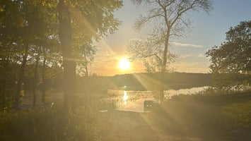 Sunrise over hazy water and a dock, symbolizing release, renewal, and new beginnings.